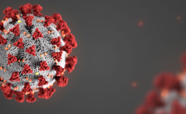 3D illustration of a COVID-19 particle, showing a grey sphere with red spike proteins protruding from its surface, set against a dark blurred background.