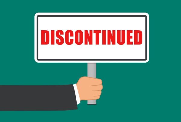 A hand in a suit holds a sign with the word DISCONTINUED written in bold red letters, hinting that Google discontinues the Scan-to-Email feature, set against a solid teal backdrop.