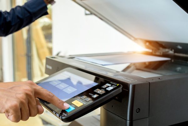A person using a photocopier, pressing buttons on the control panel while lifting the lid to scan a document—streamlining business tasks with efficient printer services.