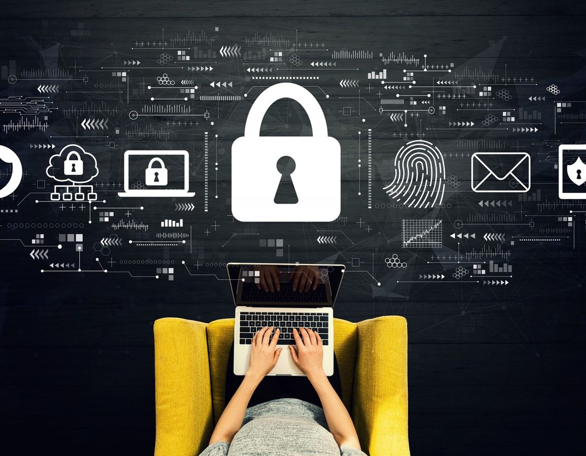 Person typing on a laptop in a yellow chair, with cybersecurity icons like a lock, fingerprint, shield, and envelope above them, representing digital security, data protection, and hybrid work security.