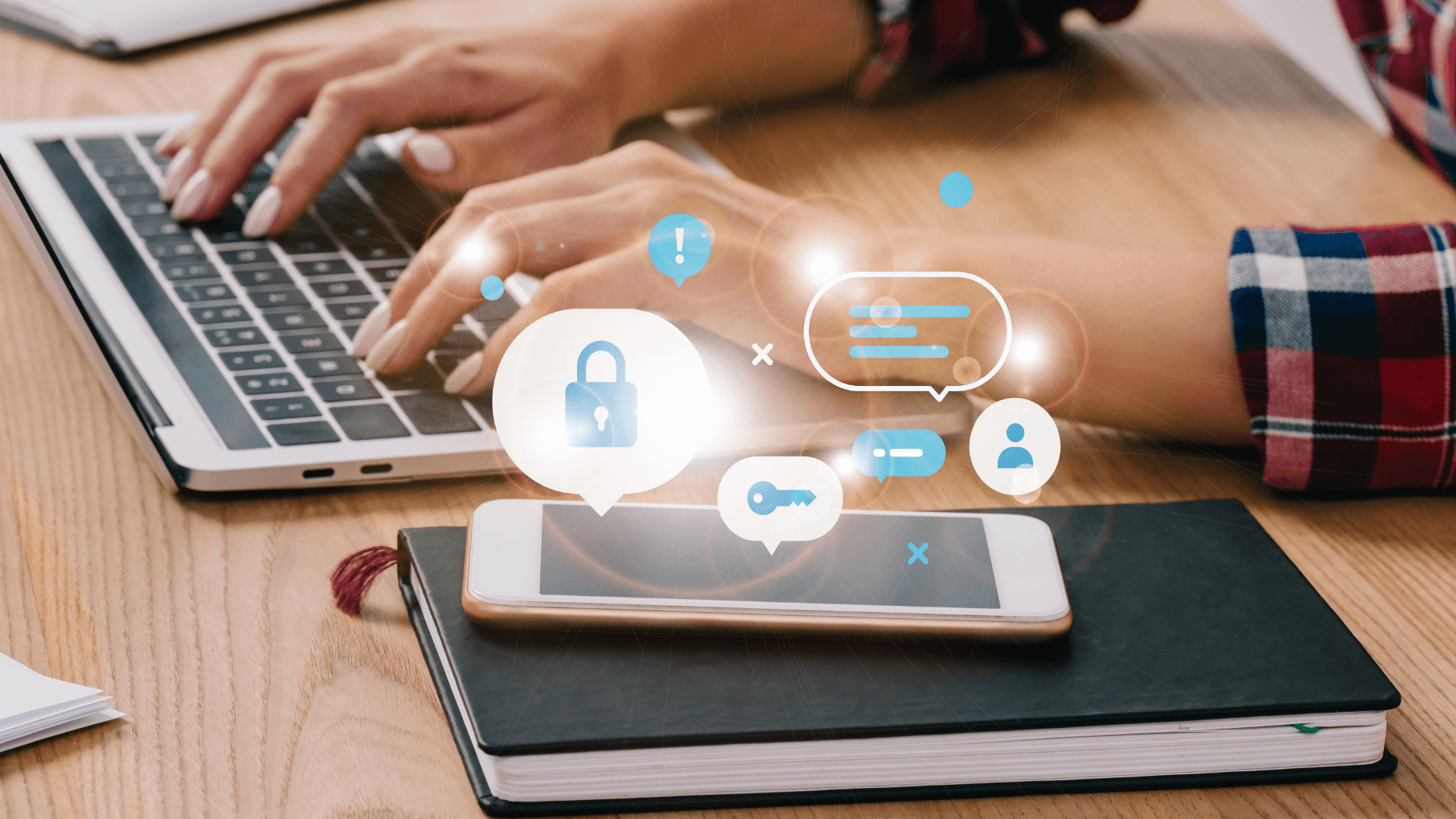 A person types on a laptop at a wooden desk with a smartphone on a notebook nearby. Digital icons appear above the phone, representing cybersecurity tips for small business owners.