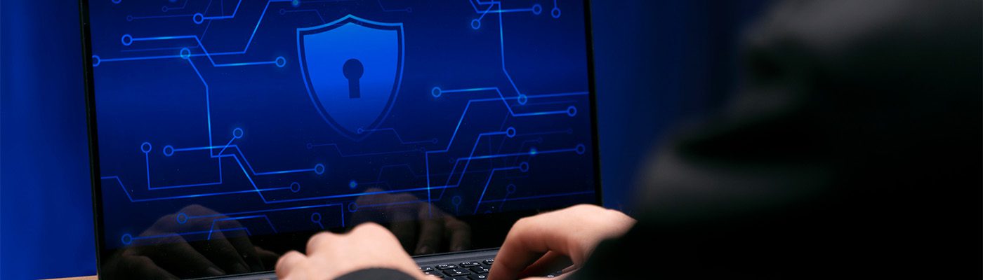 A person types on a laptop displaying a blue digital security interface with a shield and keyhole icon, highlighting business cybersecurity and advanced data protection solutions.