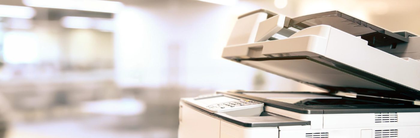 A close-up of a business copier with its lid open in a bright, modern office setting. The background is blurred, emphasizing the best copier’s control panel and scanning bed.