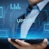 A person in a suit holding a tablet with digital icons of devices and graphs floating above it; the word UPDATE appears prominently, highlighting the need to upgrade business tech for modern success.