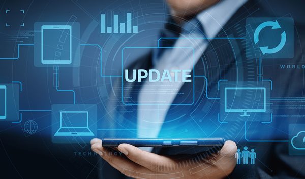 A person in a suit holding a tablet with digital icons of devices and graphs floating above it; the word UPDATE appears prominently, highlighting the need to upgrade business tech for modern success.