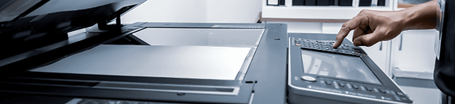 A close-up of a person's hand pressing buttons on a business printer control panel, with the copier lid open in an office setting—ideal for illustrating print maintenance or printer troubleshooting.