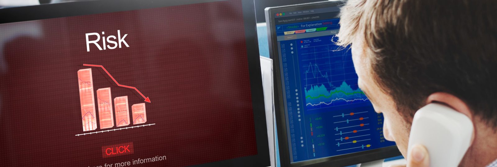 A person on the phone looks at computer screens displaying a graph with declining red bars labeled Risk and a blue financial chart with lines and data points, monitoring the effectiveness of Disaster Recovery Services.