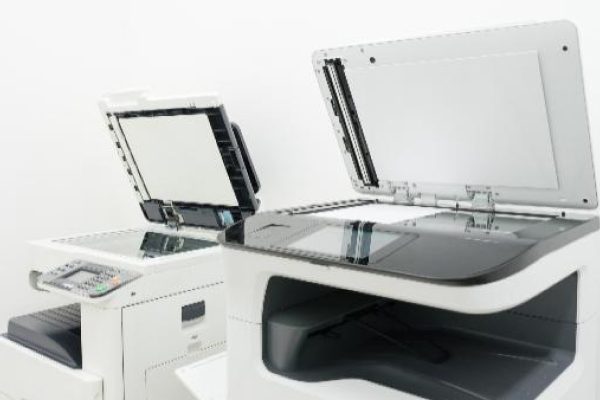 Two quality printers with their lids open are placed next to each other in a bright, minimalistic room with a white background, highlighting the benefits of advanced printer manufacturing.