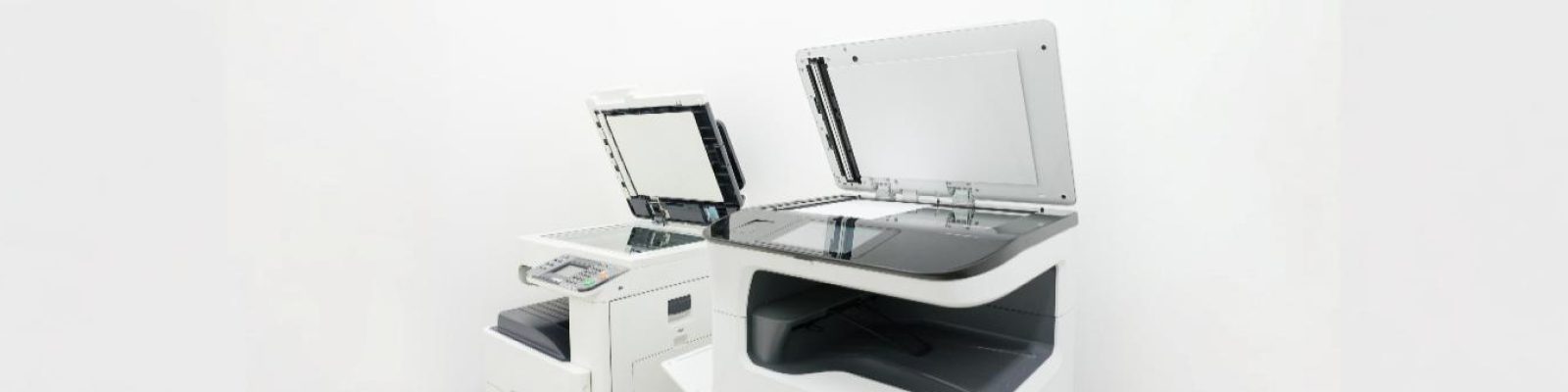 Two quality printers with their lids open are placed next to each other in a bright, minimalistic room with a white background, highlighting the benefits of advanced printer manufacturing.
