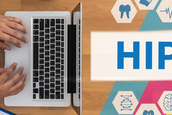 A person typing on a laptop next to a tablet, with the word HIPAA compliance displayed beside medical icons such as a heart, tooth, and stethoscope on a colorful background.