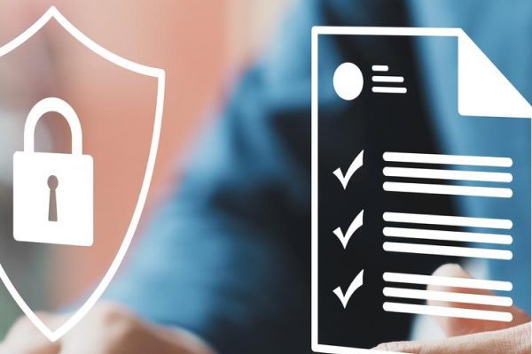 A person in a suit works at a desk with digital icons overlaid, including a shield with a padlock and a checklist, symbolizing security and illustrating the importance of cybersecurity compliance.