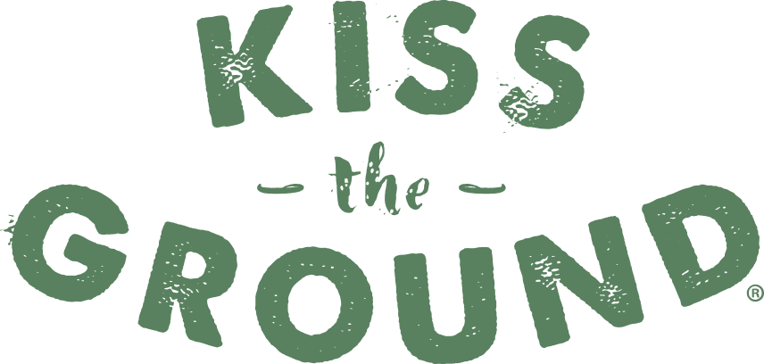 Kiss the Ground Green, textured text reads KISS the GROUND in all uppercase except for the, which is smaller and lowercase, centered between the words KISS and GROUND on a light background.