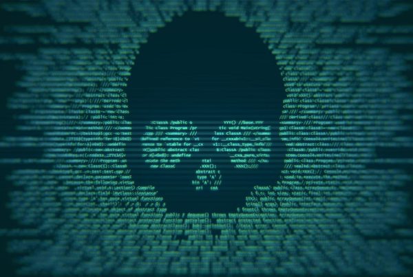 Green computer code forms the shape of a skull on a dark background, symbolizing hacking or a cyber threat. The image highlights cybersecurity risks as the skull emerges from blurred text, conveying the idea of digital danger or malware.