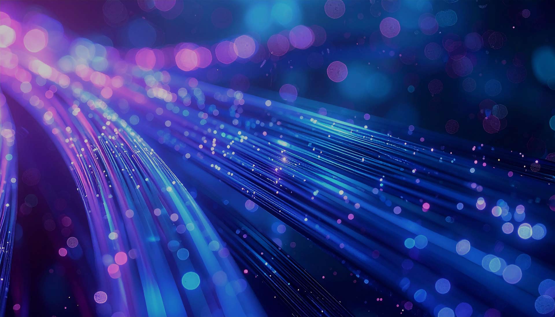 Abstract image of glowing blue and purple fiber optic cables with bokeh light effects in the background, illustrating GoodSuite’s role in enhancing efficiency and digital connectivity through innovative IT solutions.
