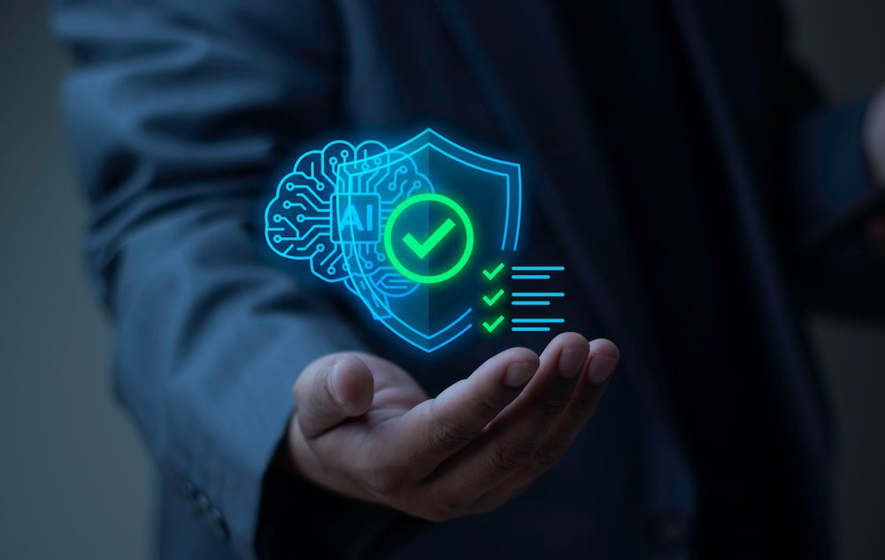 A person in a suit holds out their hand with a digital illustration of a shield, checkmarks, and an AI brain hologram, symbolizing artificial intelligence, cybersecurity, and the emerging presence of shadow AI.